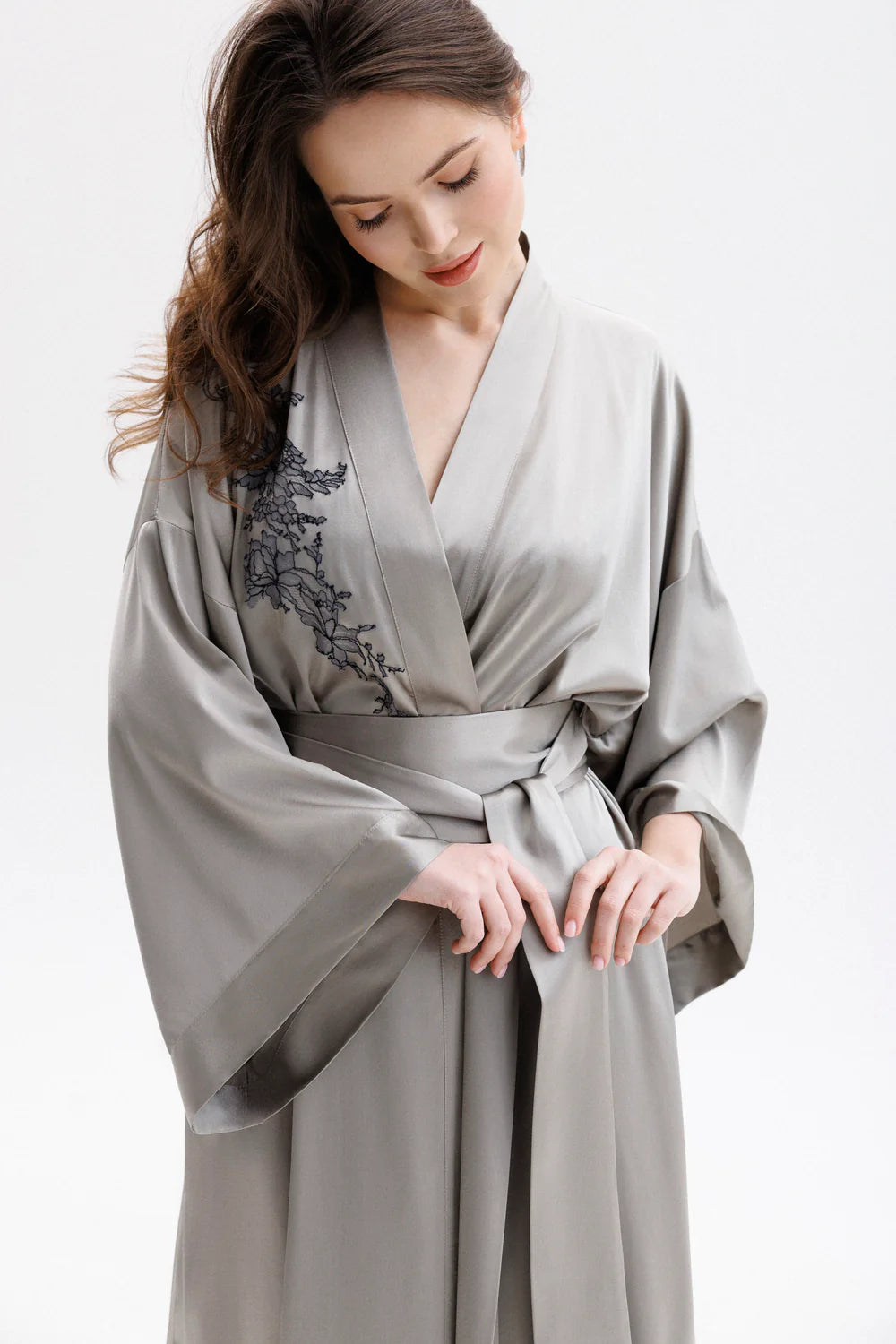 Woman wearing a long gray silk peignoir with wide silk belt, showing the front.