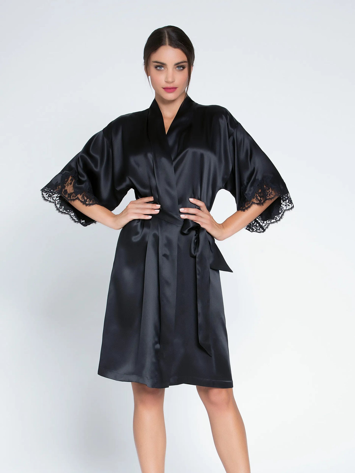 Woman wearing a black satin robe with lace sleeves on a white background
