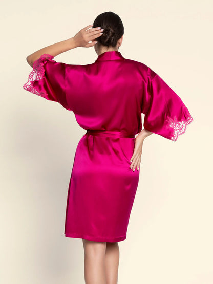 Person wearing a bright pink satin robe with lace sleeves on a beige background